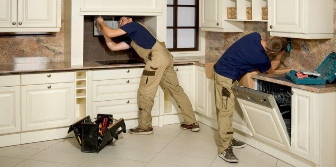 Kitchen Carpentry Two men collaborating on a kitchen counter in a spacious, well-equipped kitchen.